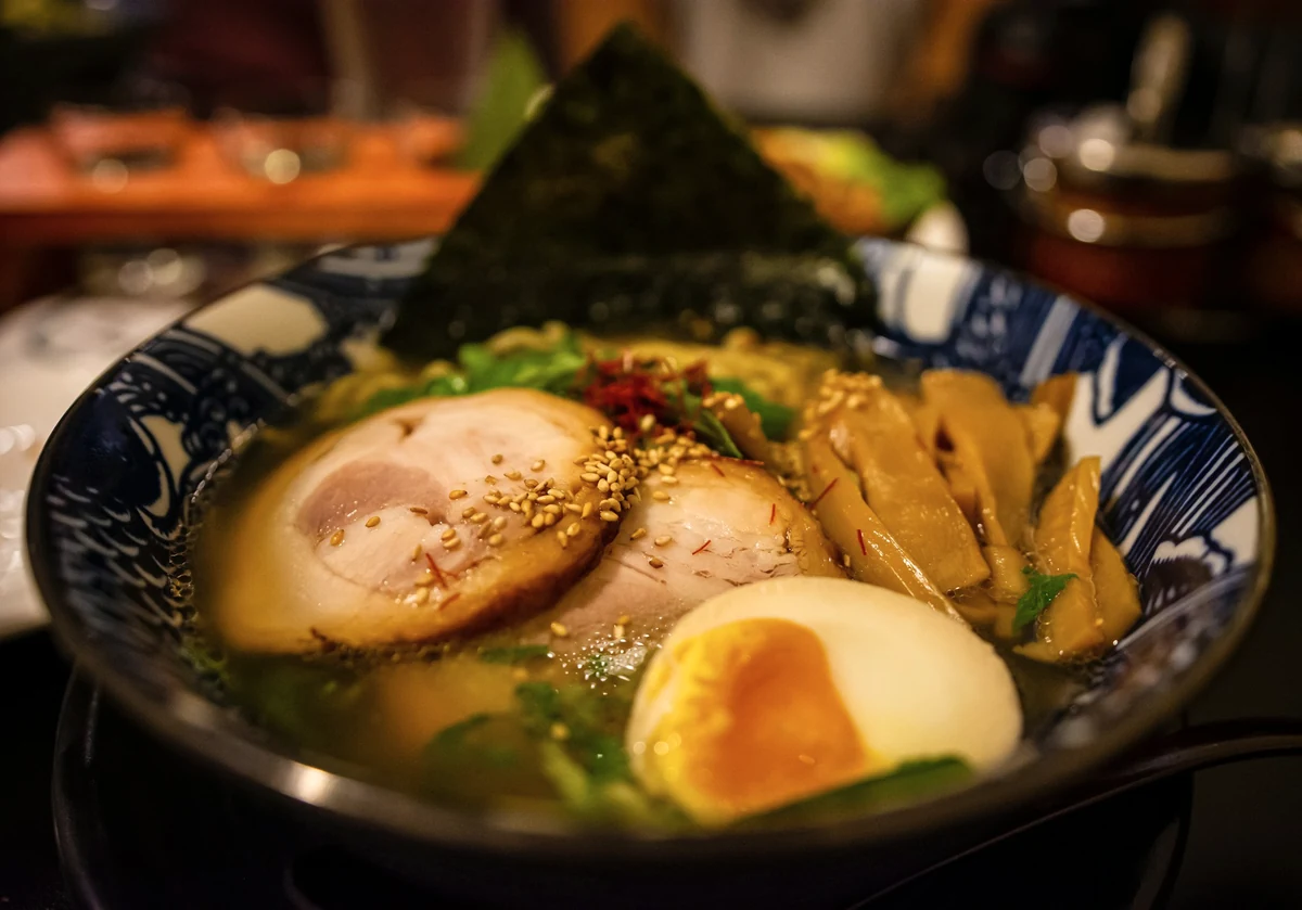 A bowl of ramen with pork, egg and spring onion